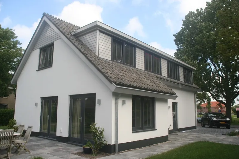 Hetzelfde vrijstaande woonhuis na afloop, met witte gevels, een donkere plint en donkere kozijnen.